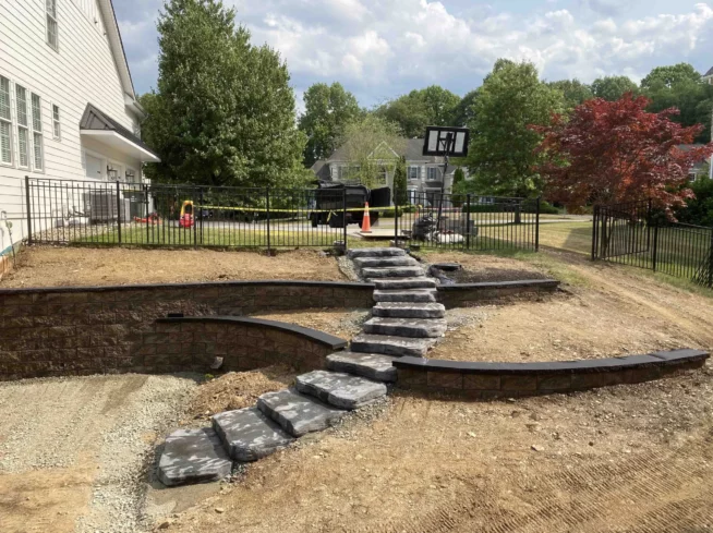 ScapeWorx team constructing a stone staircase with precision, creating a durable outdoor feature.