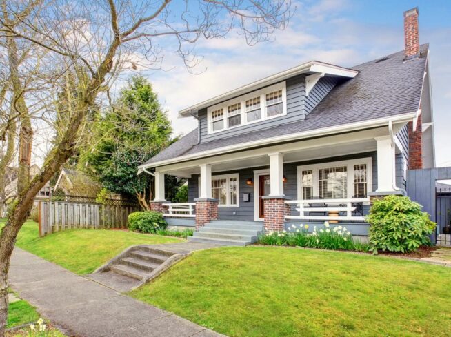 Front yard with manicured lawn and a charming blue Craftsman-style house