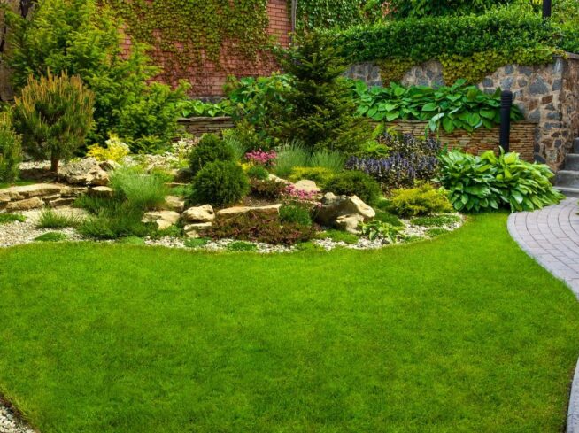 Tiered backyard landscape design with natural stone, vibrant plants, and paver walkway.
