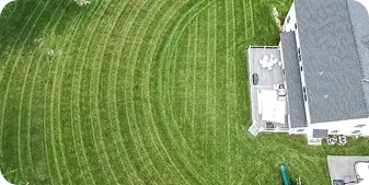 Aerial view of freshly mowed lawn with perfect circular mowing patterns around a suburban home in Media, PA