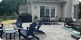 Spacious backyard paver patio with fire pit, Adirondack chairs, and outdoor dining set at a Glen Mills, PA home