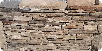 Dry-stacked natural stone retaining wall with a rustic finish, showcasing skilled masonry work and durable landscape construction.