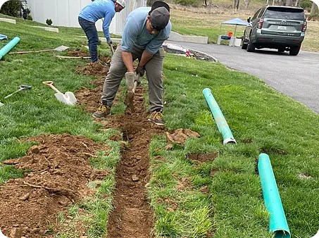 ScapeWorx crew trenching and installing green drainage pipe
