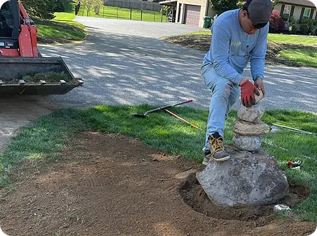 ScapeWorx Team member arranging decorative stacked stones during landscape redesign