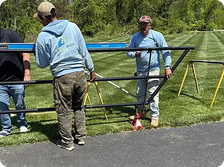 ScapeWorx crew installing custom fence with level and brackets