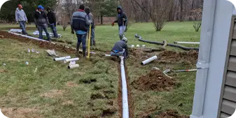 Crew installing underground drainage system in residential backyard