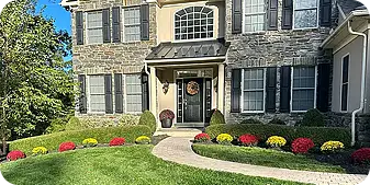 Front walkway with colorful mums and stone façade.