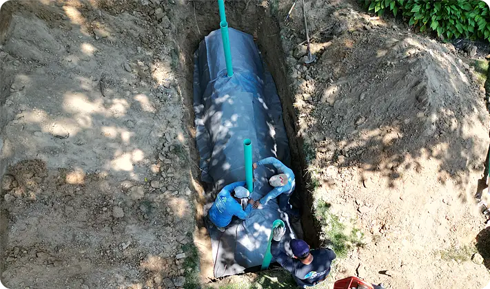Overhead view of a drainage system installation with ScapeWorx crew working in a trench.