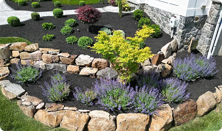 Scape Worx designed this tiered stone retaining wall with flowering plants and colorful landscaping
