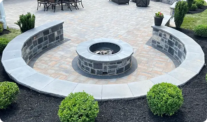 Circular fire pit with matching stone seating wall and paver patio by ScapeWorx