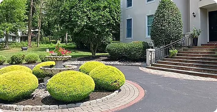 Symmetrical foundation landscaping by ScapeWorx with bold shrubs and brick circle driveway
