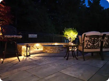 Cozy fire pit area with stone seating walls and lighting at dusk