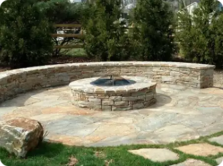 Natural stone fire pit surrounded by a circular stone seating wall