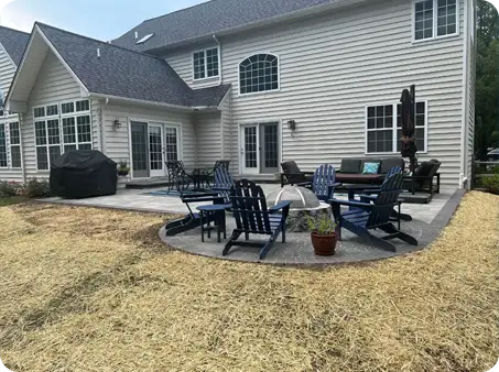 Backyard patio with blue Adirondack chairs and a circular fire pit area