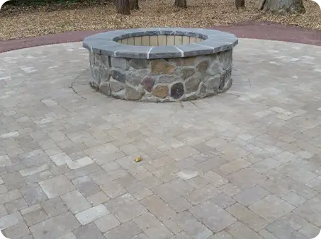 Circular stone fire pit surrounded by paver patio