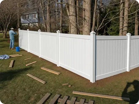 ScapeWorx crew installing white vinyl privacy fence in residential backyard