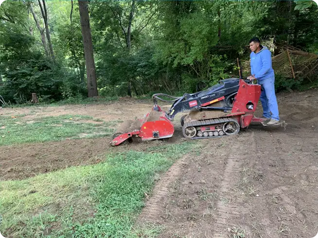 ScapeWorx team member using specialized equipment for grading and soil preparation to ensure proper lawn installation and drainage.