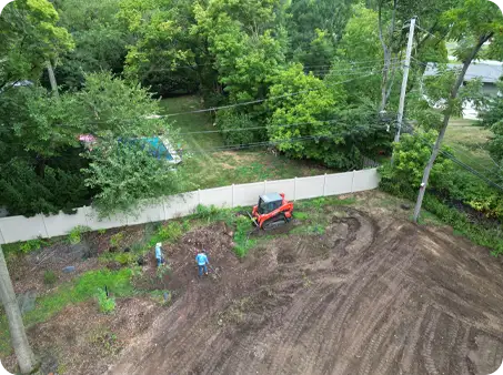 ScapeWorx team grading and clearing backyard area with skid steer and hand tools to prepare for new landscaping and lawn installation.