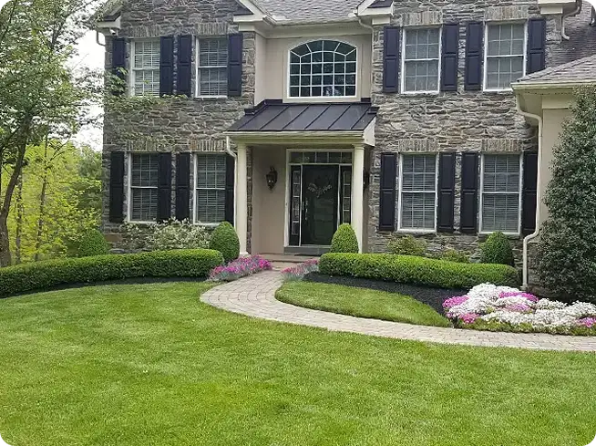 Vibrant, green lawn showcasing tidy flower beds and sharp edging, following lawn care and fertilization from ScapeWorx.