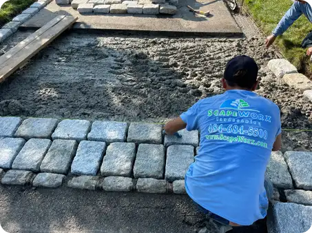 ScapeWorx team installing stone pavers for a walkway with careful precision.
