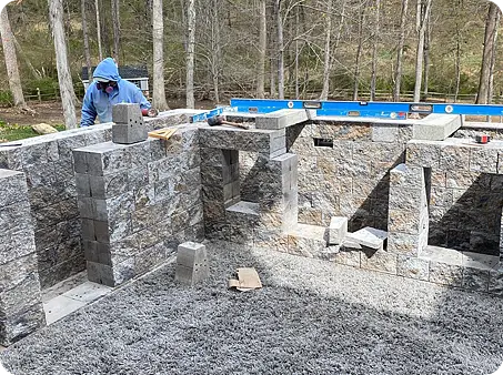 ScapeWorx team building a stone wall with precise measurements, ensuring a solid foundation.