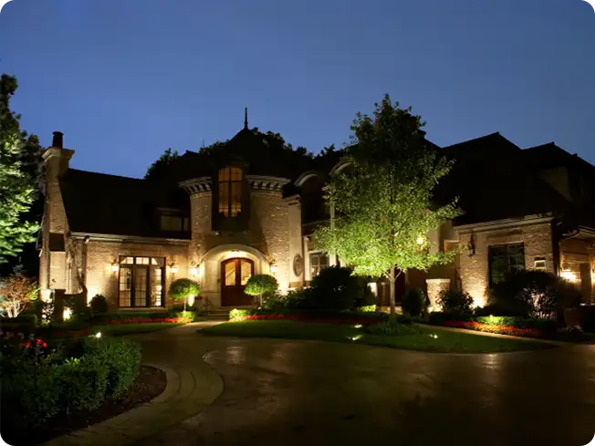 Luxury estate illuminated by ScapeWorx landscape lighting, with uplights accenting trees and architectural details for a refined and secure nighttime setting.