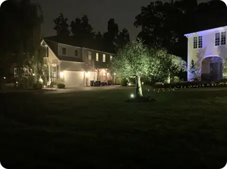 ScapeWorx landscape lighting illuminating a two-story home and trees, providing subtle security and nighttime visibility.