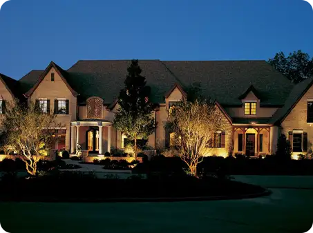 ScapeWorx architectural and landscape lighting illuminating a large estate home, accentuating trees and structural features for a dramatic nighttime presence.