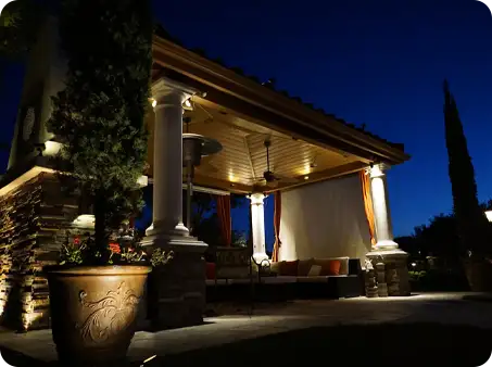 ScapeWorx outdoor lighting highlighting a luxurious pavilion with stone columns and warm accent lights for nighttime relaxation and entertaining.