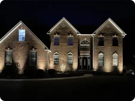ScapeWorx landscape lighting highlighting brick home exterior at night.