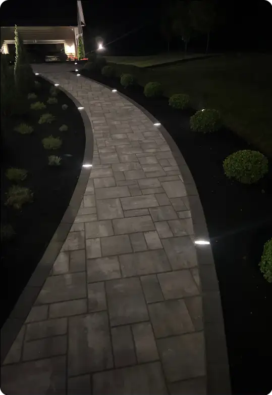 ScapeWorx illuminated paver walkway with landscape lighting at night.