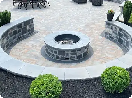 Circular stone fire pit with surrounding seating area on a brick patio.