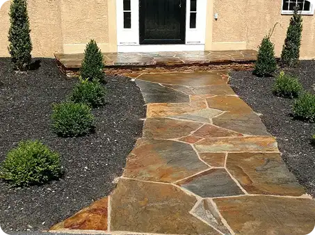 Sealed natural stone walkway with vibrant colors, surrounded by freshly mulched garden beds.