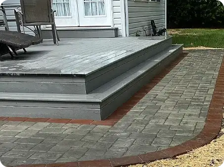 Sealed paver pathway around a deck, with a contrasting brick border and clean finish.