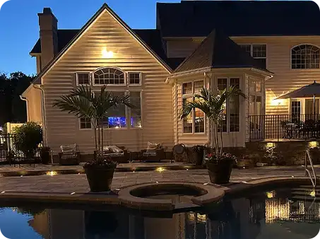 Poolside patio at night with lighting and cozy seating