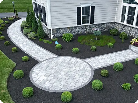 Elegant stone pathway with circular features surrounded by hand trimmed shrubs.