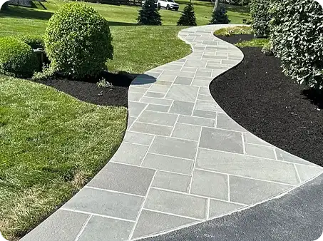 Superbly curved walkway made of high-quality stone pavers surrounded by well-maintained landscaping.