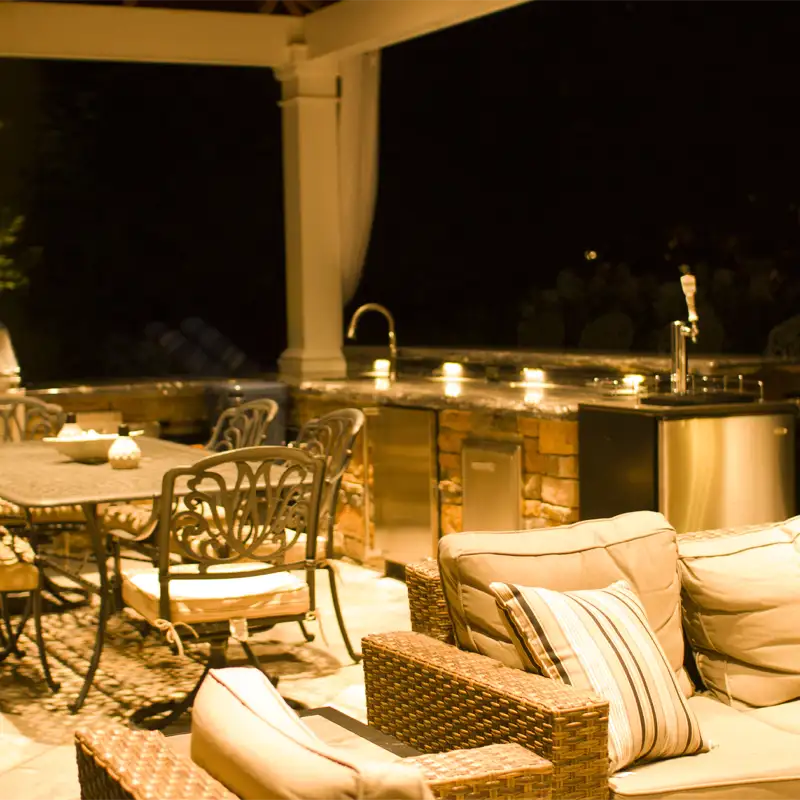 Illuminated outdoor kitchen and dining area by ScapeWorx