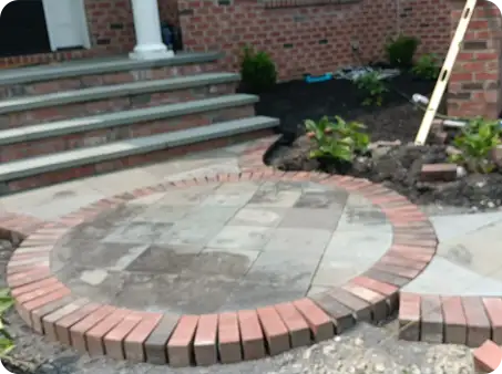 Circular paver medallion installed by ScapeWorx with brick border near house entrance during repair.