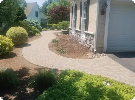 ScapeWorx designed this winding paver walkway leading to a house, surrounded by landscaping.