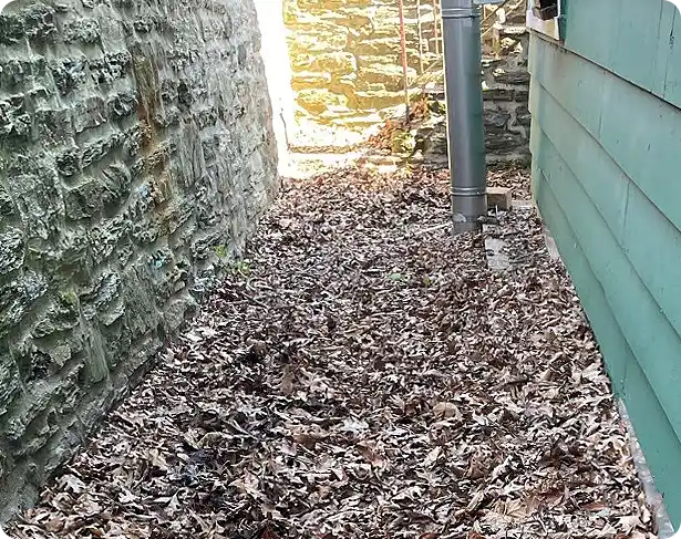 fall clean up Concordville with leaves piled in a narrow stone alleyway