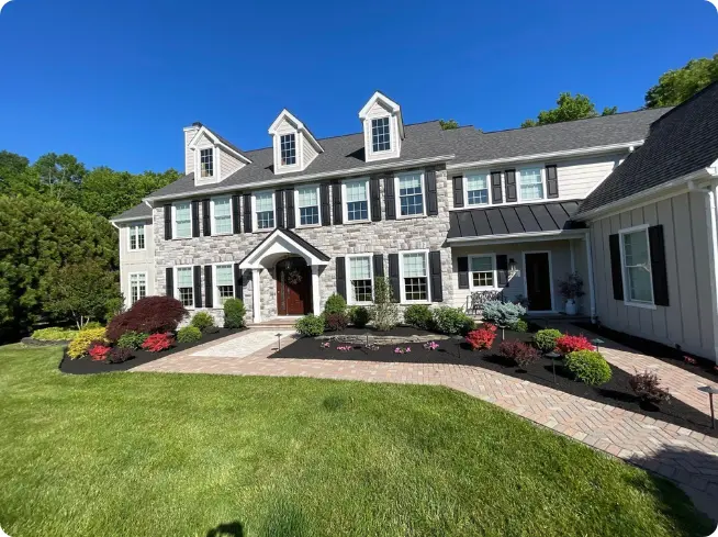 ScapeWorx front yard landscape maintenance with black mulch beds, colorful annuals, trimmed shrubs, and brick walkway