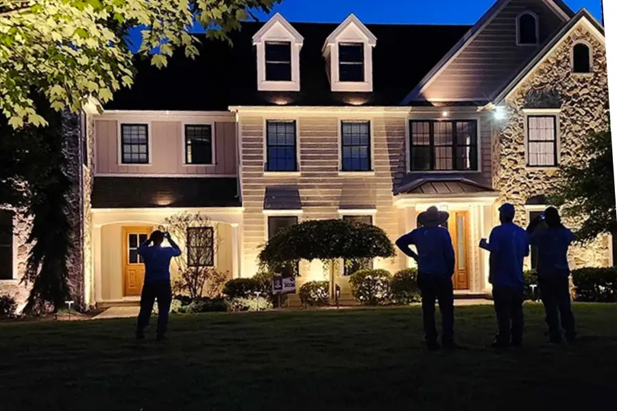 Stone home illuminated with architectural landscape lighting at night