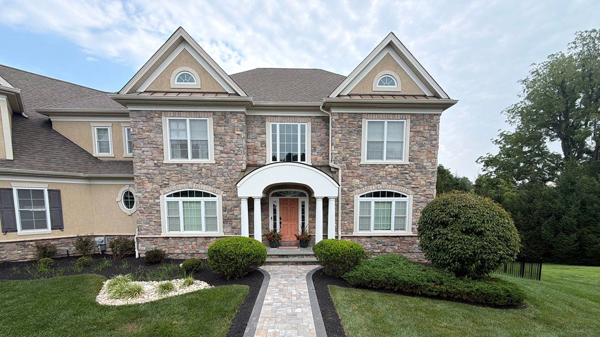 Stone-front Glen Mills home with a walkway to the front door and clipped foundation shrubs